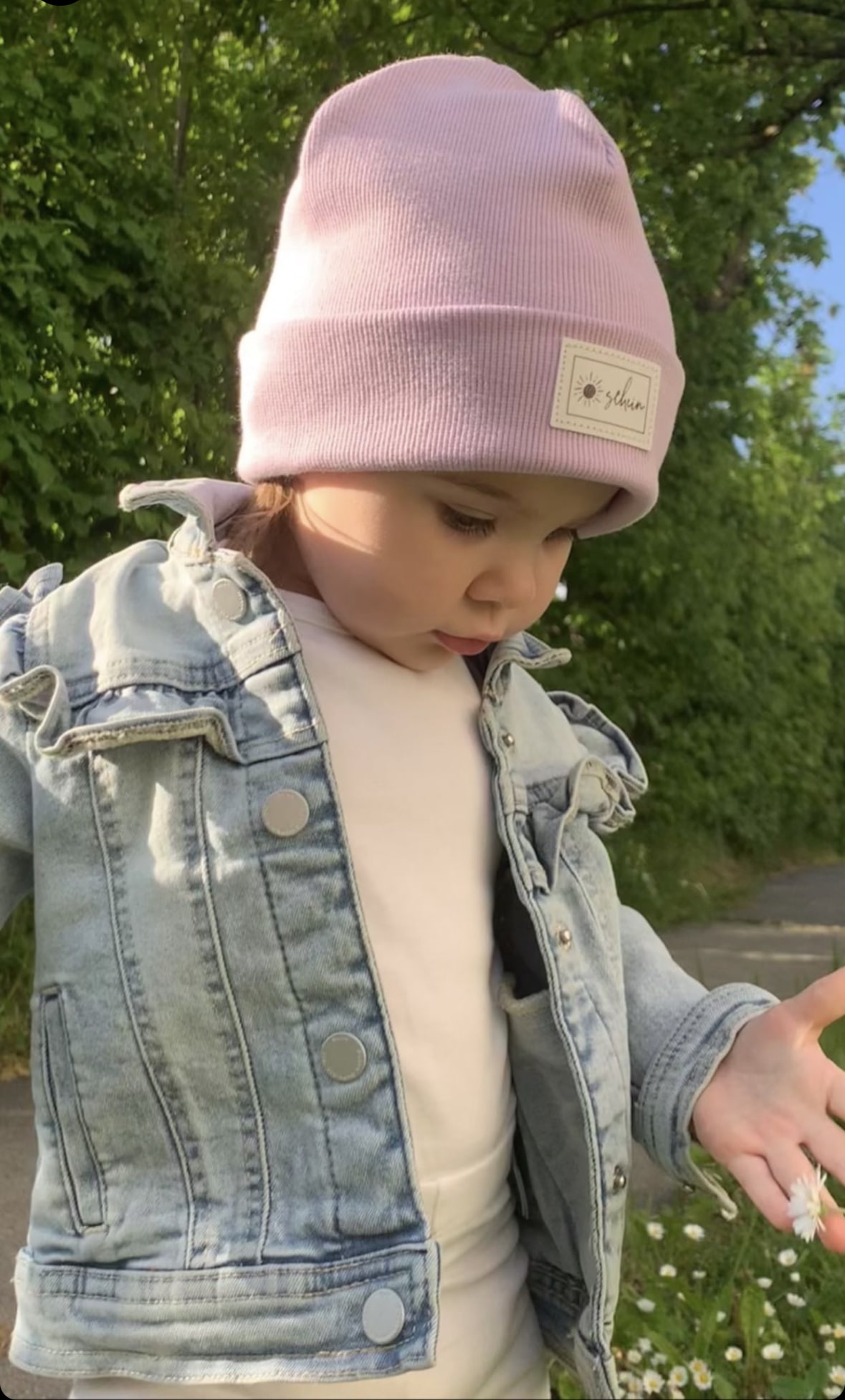 Kleinkind mit fliederfarbener Beanie das auf dem Spielplatz spielt